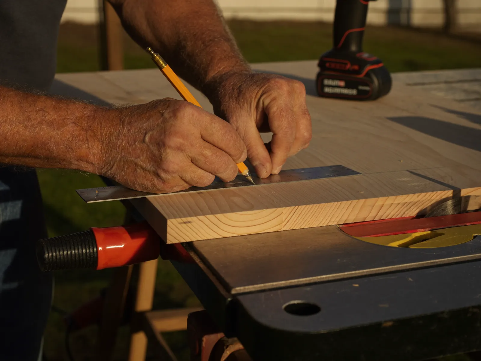A carpenter marking a timber board in golden afternoon light
